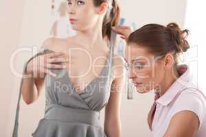 Female fashion designer pinning dress on model