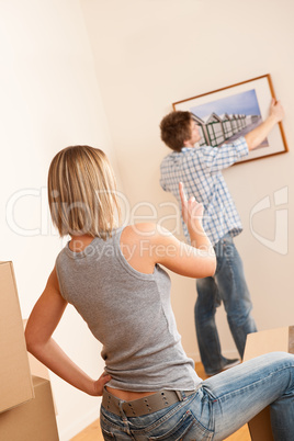 Moving house: Couple hanging picture on wall