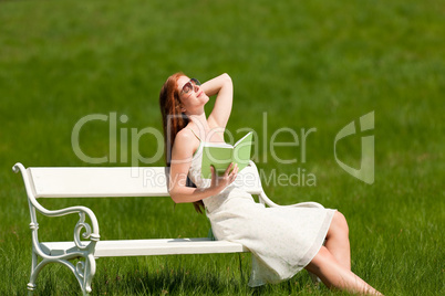 Red hair woman relaxing on white bench in spring