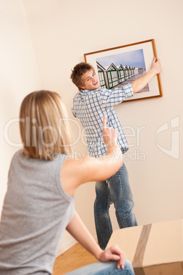 Moving house: Couple hanging picture on wall