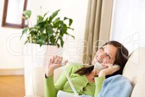 On the phone home: Smiling woman calling in lounge