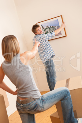 Moving house: Couple hanging picture on wall