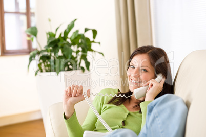 On the phone home: Smiling woman calling in lounge
