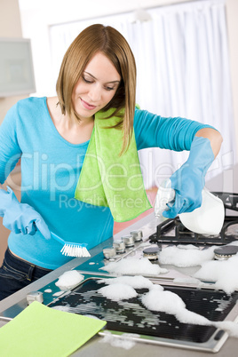 Young woman cleaning stove in modern kitchen