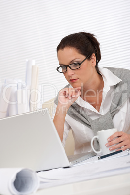 Female architect with laptop and coffee sitting