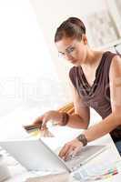 Smiling female designer with color swatch and laptop