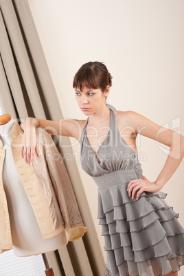 Fashion model trying gray dress in designer studio