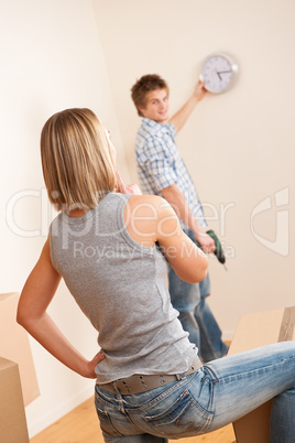 Moving house: Young couple hanging clock on wall