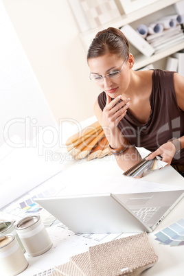 Smiling female designer with color swatch and laptop