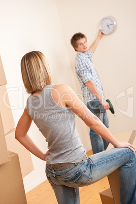 Moving house: Young couple hanging clock on wall