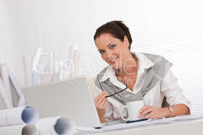 Smiling female architect with laptop and coffee
