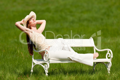 Red hair woman with hat enjoying sun on white bench in spring