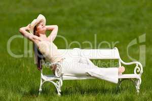 Red hair woman with hat enjoying sun on white bench in spring