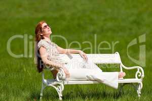 Red hair woman relaxing on white bench in spring