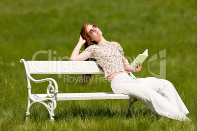Red hair woman reading book on white bench in spring