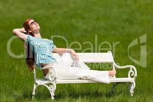 Red hair woman relaxing on white bench in spring