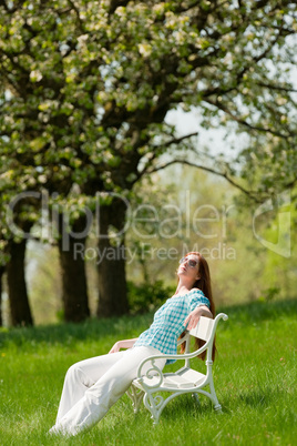 Young woman relaxing under blossom tree in spring