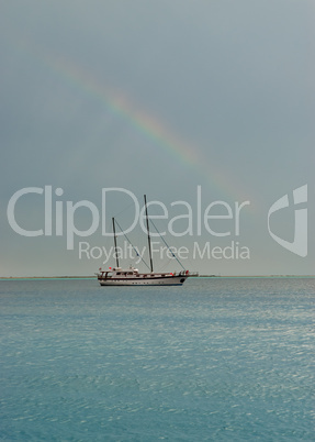 Rainbow flat sea and sailing boat