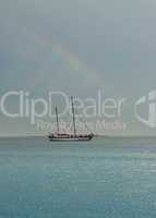 Rainbow flat sea and sailing boat