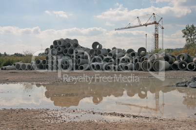 Betonrohre und Baukran spiegeln sich in Pfütze