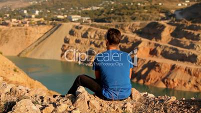 A man rests on a flooded quarry