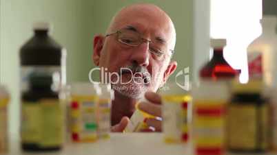 Older man choosing pills from medicine cabinet