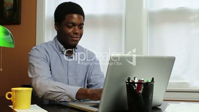 Man typing at computer, laughing