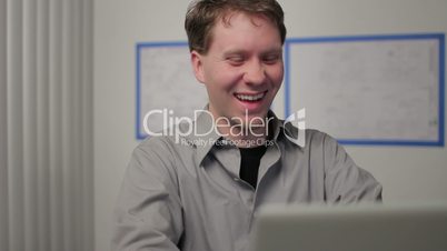 Young man laughing at his laptop