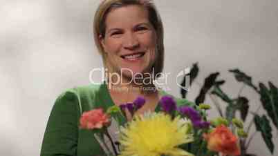 Woman arranging flowers, looking at camera