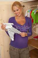 Pregnant woman with baby clothes