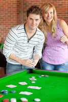Caucasian couple playing cards on a billiard
