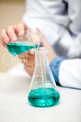 Male chemist pouring a blue liquid