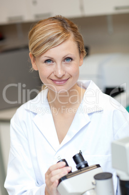 Smiling female scientist using a microscope