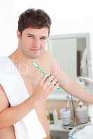 man with a towel brushing his teeth