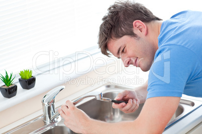 Self-assured man repairing his sink in the kitchen