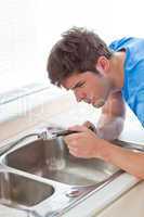 man repairing his sink in the kitchen