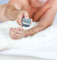 man holding a remote lying on his bed