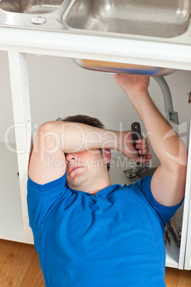 man repairing his sink in the kitchen