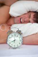 man lying in bed with alarm clock