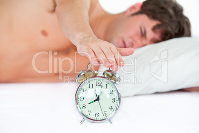 man stopping his ringing alarm clock