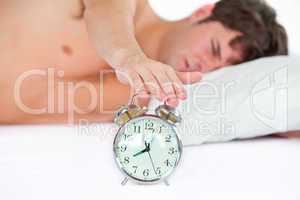 man stopping his ringing alarm clock