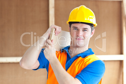 male worker with a yellow helmet carrying a wood