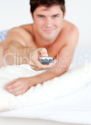 man holding a remote lying on his bed