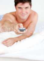 man holding a remote lying on his bed