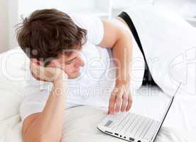 man using a laptop lying on his bed