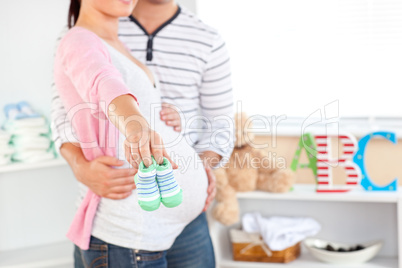 pregnant woman holding baby shoes