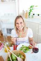 Smiling woman eating salad in the kitchen