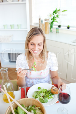 Cute woman eating salad in the kitchen