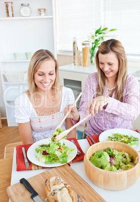 female friends eating salad in the kitchen