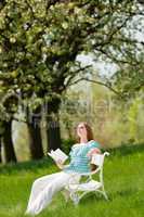 Young woman relaxing under blossom tree in spring